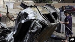 People inspect a destroyed car in front of the provincial council building of Tikrit, 80 miles (130 kilometers) north of Baghdad, Iraq, March 30, 2011