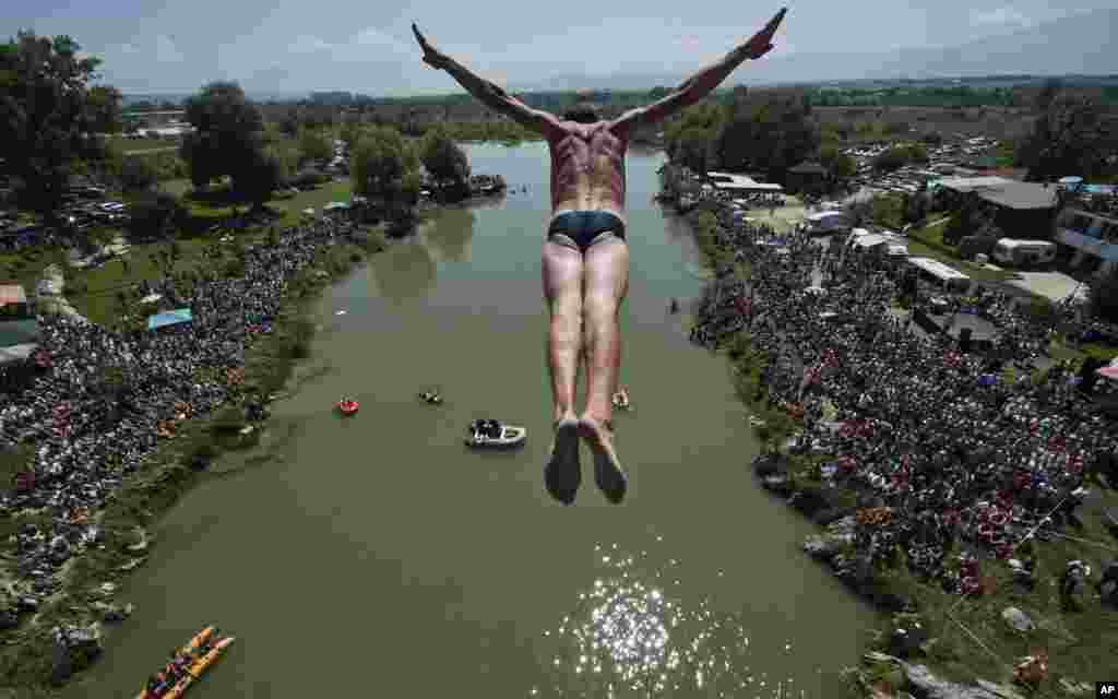 Spectators watch as a diver Sali Riza Grancina, winner of the competition, performs the winning jump from the Ura e Shenjte bridge during the traditional annual high diving competition, near the town of Gjakova, 100 km south of the Kosovo capital Pristina. A total of 27 divers from Kosovo competed, diving from the 22-meter-high bridge into the Drini i Bardhe River.