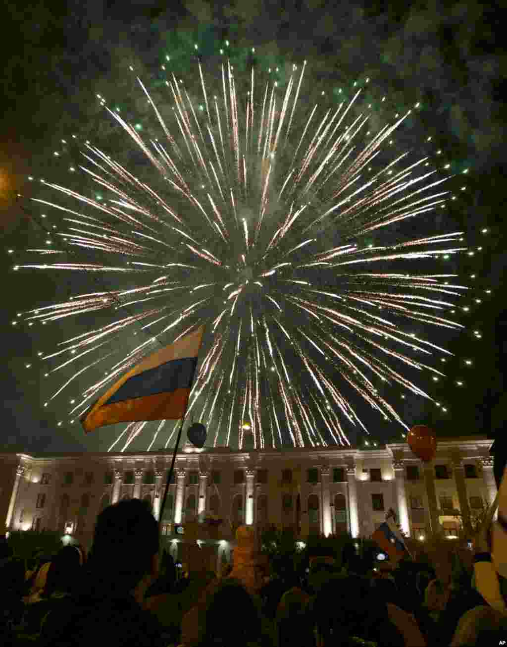 People watch fireworks at the central Lenin Square in Simferopol, Crimea, Mar, 21, 2014. Russian President Vladimir Putin completed the annexation of Crimea, signing a law making the Black Sea peninsula part of Russia.