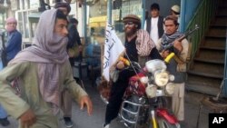 FILE - A Taliban fighter sits on his motorcycle adorned with a Taliban flag in a street in Kunduz, Afghanistan. Afghanistan’s Taliban closed ranks around a new leader after months of infighting following the death of Mullah Mohammad Omar, Sept. 29, 2015.