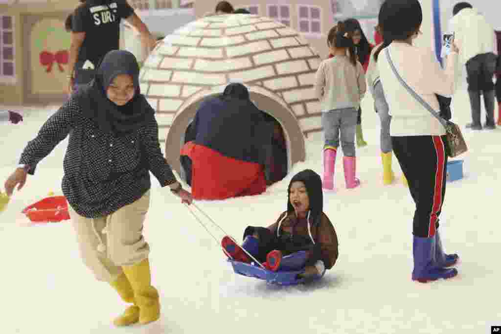 Visitantes juegan en la nieve artificial en una escena invernal para celebrar las próximas vacaciones de Navidad en Serpong, en las afueras de Yakarta, Indonesia.