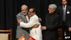 Indian Prime Minister Narinder Modi, left, and Jammu and Kashmir Deputy Chief Minister Nirmal Singh, center, embrace as Jammu and Kashmir Chief Minister Mufty Mohammed Sayeed looks on during a swearing-in ceremony of the state assembly in Jammu, March 1, 2015.