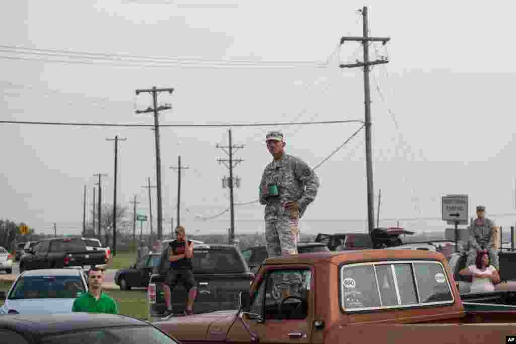 Military personnel and civilians wait in a parking lot outside the Fort Hood military base for updates about the shooting that occurred inside, April 2, 2014.