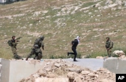 Handcuffed and blindfolded Osama Hajahjeh, 16, runs away from Israeli soldiers near the village of Tekoa, West Bank, Apri 18, 2019.