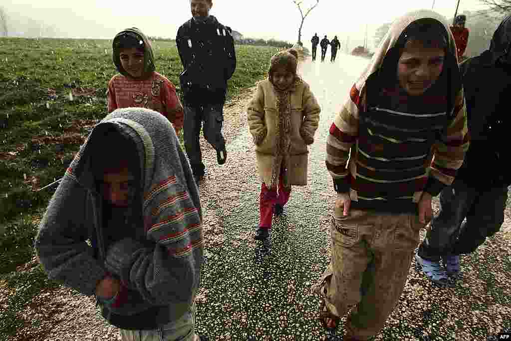 Trẻ em Syria trốn khỏi thành phố Idlib đi dưới một trận mưa đá bên ngoài một trại tị nạn gần biên giới Thổ Nhĩ Kỳ-Syria, ngày 16 tháng 2 năm 2012. (Reuter)