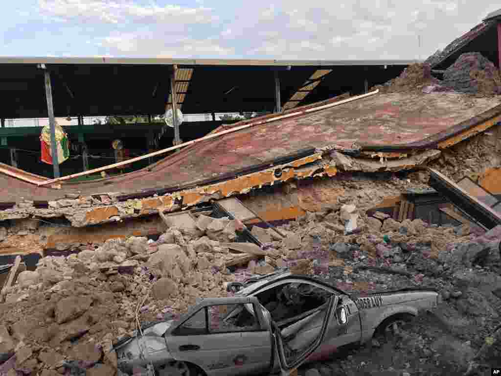 A car sits crushed, engulfed in a pile of rubble from a building felled by a 7.1 earthquake, in Jojutla, Morelos state, Mexico, Sept. 19, 2017. 