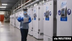 FILE - A worker passes a line of freezers holding coronavirus disease (COVID-19) vaccine candidate BNT162b2 at a Pfizer facility in Puurs, Belgium in an undated photograph. 