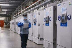 FILE - A worker passes a line of freezers holding coronavirus disease vaccine candidate BNT162b2 at a Pfizer facility in Puurs, Belgium, in an undated photograph.