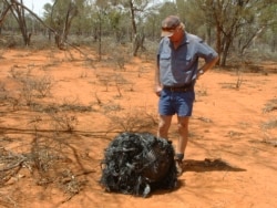 Australian farmer James Stirton stands next to a ball of twisted metal, purported to be fallen space junk, on his farm in southwestern Queensland in this undated handout photograph received March 28, 2008.