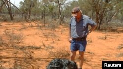 Australian farmer James Stirton stands next to a ball of twisted metal, purported to be fallen space junk, on his farm in southwestern Queensland in this undated handout photograph received March 28, 2008.