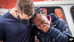 A woman is comforted outside the historical home of Anglican Archbishop Desmond Tutu, in Soweto, Johannesburg, South Africa, Dec. 27, 2021.