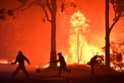Rural Fire Service (RFS) volunteers and NSW Fire and Rescue officers fight a bushfire encroaching on properties near Termeil, Australia, Dec. 3, 2019.