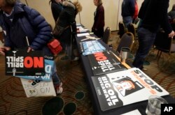 Signs opposing offshore oil drilling are distributed, March 5, 2018, at a hearing in Olympia, Wash., organized by a coalition of environmental groups opposed to the Trump administration's proposal to expand offshore oil drilling off the Pacific Northwest