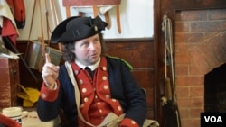 El oficial Doug Gio, con uniforme militar de la época colonial, explica en la planta baja de la comisaría en el centro de Williamsburg, el uso de cada una de las armas y periódicamente hace demostraciones en exteriores sobre los artefactos. [Foto: Tomás Guevara / VOA].