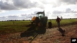 FILE - A farmer walks next to his tractor at a farm near Parkes, 357 kilometers west of Sydney, Australia. Agriculture is a key focus of the delegation. 