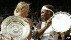 ARCHIVES - La star du tennis russe Maria Sharapova, à gauche, tient le trophée du vainqueur et Serena Williams celui de la finaliste après la présentation de la finale du simple dames sur le court central de Wimbledon, le 3 juillet 2004.