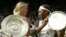 ARCHIVES - La star du tennis russe Maria Sharapova, à gauche, tient le trophée du vainqueur et Serena Williams celui de la finaliste après la présentation de la finale du simple dames sur le court central de Wimbledon, le 3 juillet 2004.