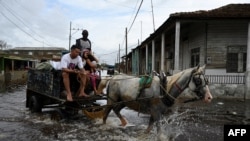 ARCHIVO - Personas viajan en un carro a través de aguas inundadas después del paso del huracán Rafael en Batabano, provincia de Artemisa, Cuba, el 7 de noviembre de 2024.
