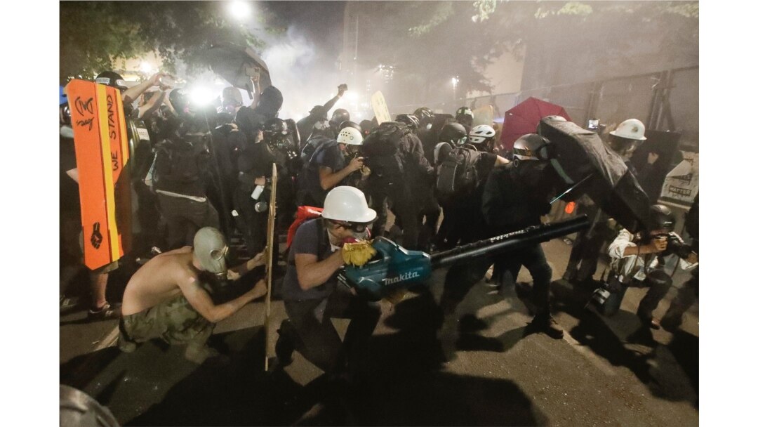 Demonstrators huddle and blow back tear gas with leaf blowers during clashes with federal officers during a Black Lives Matter protest at the Mark O. Hatfield United States Courthouse, July 29, 2020, in Portland, Ore.