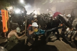 Demonstrators huddle and blow back tear gas with leaf blowers during clashes with federal officers during a Black Lives Matter protest at the Mark O. Hatfield United States Courthouse, July 29, 2020, in Portland, Ore.