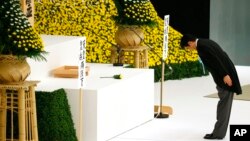 Japanese Prime Minister Shinzo Abe bows before the main altar decorated with huge bank of chrysanthemums as he offers prayers for the war dead during a memorial service at Nippon Budokan martial arts hall in Tokyo, Aug. 15, 2015. J