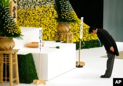 FILE - Japanese Prime Minister Shinzo Abe bows before the main altar decorated with huge bank of chrysanthemums as he offers prayers for the war dead during a memorial service at Nippon Budokan martial arts hall in Tokyo, Aug. 15, 2015.