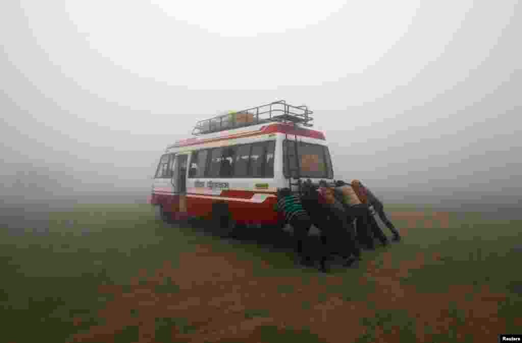 Passengers push their bus amid dense fog on a cold winter morning on the outskirts of Agartala, capital of India&#39;s northeastern state of Tripura. 