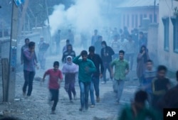 Police use teargas smoke to disperse protesters as Kashmiri Muslim villagers gather near the house of Zahid Ahmed before his body arrived at Batango village, south of Srinagar, Indian-controlled Kashmir, Oct. 18, 2015.