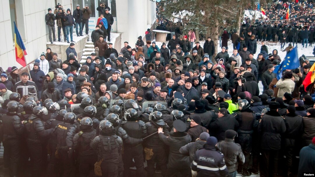 Protesters push a riot police line outside the parliament building in Chisinau, Moldova, Jan. 20, 2016. Hundreds of protesters broke through police lines on Wednesday to get into Moldova's parliament after it voted in a new prime minister.