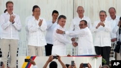 ປະທານາທິບໍດີ ໂຄລອມເບຍ ທ່ານ Juan Manuel Santos ແຖວໜ້າຊ້າຍ ແລະຜູ້ບັນຊາການ ກຸ່ມກຳລັງ FARC ​ທ່ານ Rodrigo Londono ກຳລັງສຳພັດມືກັນ.