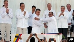 ປະທານາທິບໍດີ ໂຄລົມເບຍ ທ່ານ Juan Manuel Santos, ໜ້າຊ້າຍ, ແລະ ຜູ້ບັນຊາການຂັ້ນສູງຂອງກອງກຳລັງປະຕິວັດ
ປະກອບອາວຸດແຫ່ງ ໂຄລົມເບຍ ທ່ານ Rodrigo Londono, ຈັບມືກັນຫຼັງຈາກເຊັນຂໍ້ຕົກລົງສັນຕິພາບ.