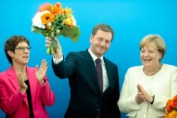 German Chancellor Angela Merkel, right, and Christian Democratic Union party's chairwoman Annegret Kramp-Karrenbauer, left, applause to Governor of Saxony Michael Kretschmer prior to a party's board meeting, Sept. 2, 2019.