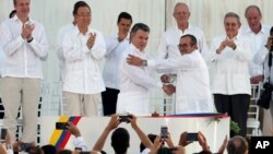 Presiden Kolombia Juan Manuel Santos (tengah kiri) berjabat tangan dengan komandan tertinggi pemberontak FARC, Rodrigo Londono usai penandatanganan perjanjian damai di Cartagena, Senin (26/9).