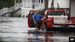 A Mississippi man lifts his left leg to remove water from his boot after wading through Isaac's flood waters 