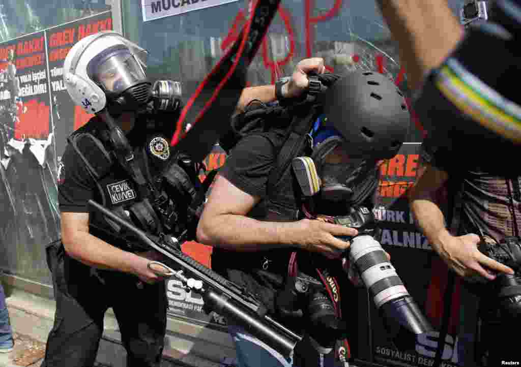 A Turkish riot police officer pushes a photographer during a protest in Taksim Square in Istanbul, June 11, 2013.&nbsp;