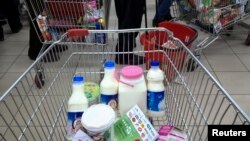 FILE - Food items are placed in trolleys as customers stand in line to pay for their goods at a shopping mall in northwestern Tehran, Iran.