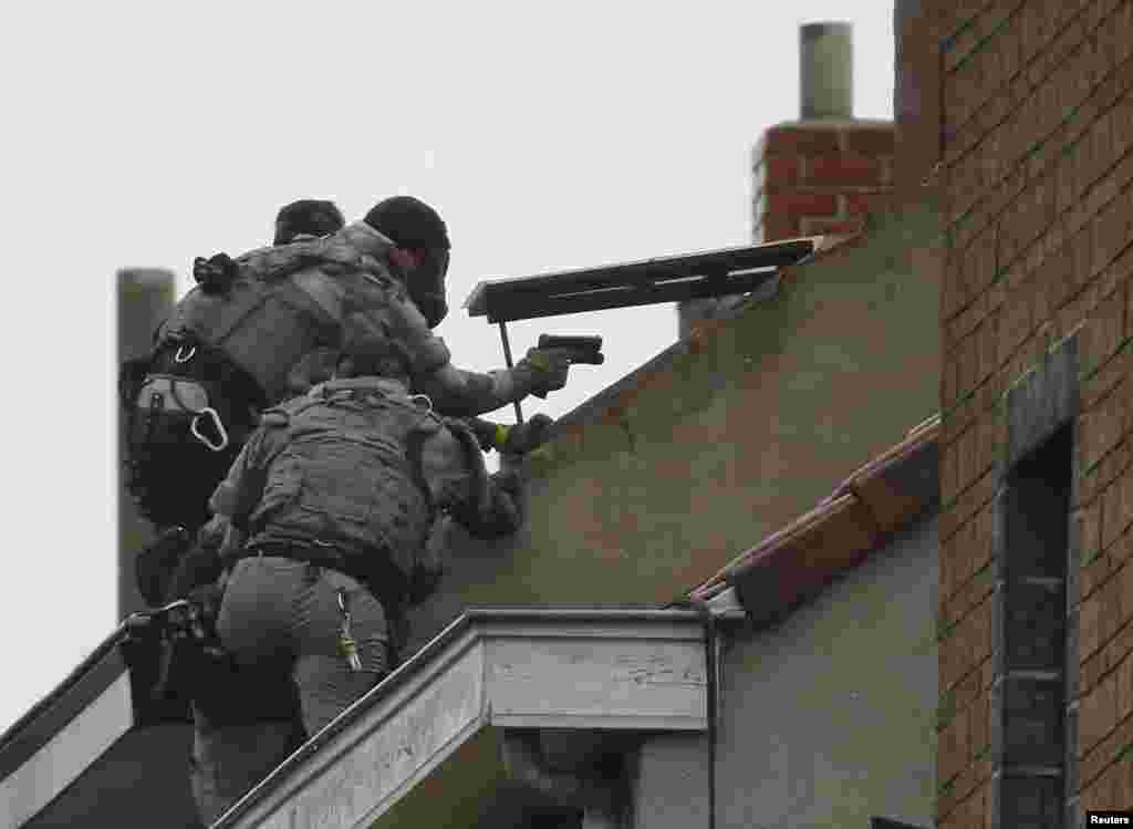 Belgian special forces police climb on an apartment block during a raid, in search of suspected Muslim fundamentalists linked to the deadly attacks in Paris, in the Brussels suburb of Molenbeek.