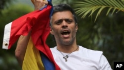 Tokoh oposisi Venezuela Leopoldo Lopez memegang bendera nasional saat menyambut pendukungnya di rumahnya di Caracas, Selasa (1/8). 