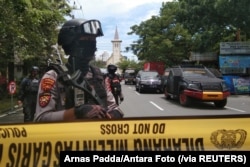 Para polisi bersenjata menjaga sepanjang jalan yang sudah ditutup menyusul ledakan di luar Gereja Katedral di Makassar, Sulawesi Selatan, Minggu, 28 Maret 2021. (Foto: Arnas Padda/Antara Foto via Reuters)