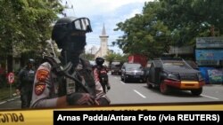 Para polisi bersenjata menjaga sepanjang jalan yang sudah ditutup menyusul ledakan di luar Gereja Katedral di Makassar, Sulawesi Selatan, Minggu, 28 Maret 2021. (Foto: Arnas Padda/Antara Foto via Reuters)