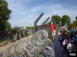 FILE - Refugees and migrants find a border fence of razor wire at the Serbia-Hungary border crossing, Sept. 15, 2015. (Henry Ridgwell/VOA)