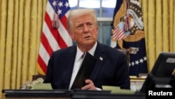 President Donald Trump signs documents as he issues executive orders and pardons for Jan. 6 defendants in the Oval Office at the White House on Inauguration Day in Washington, Jan. 20, 2025. 