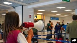 Passengers arriving in Rome from four Mediterranean countries receive instructions by airport staff, right, as they line up with their suitcases at Rome's Leonardo da Vinci airport to be immediately tested for COVID-19, Aug.16, 2020. 