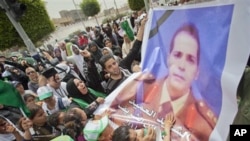 In this photo made on a government organized tour, supporters carry a poster of Libyab army colonel who was killed in NATO attack in April, during funeral ceremony for members Gadhafi family in Tripoli, Libya, May 2, 2011.