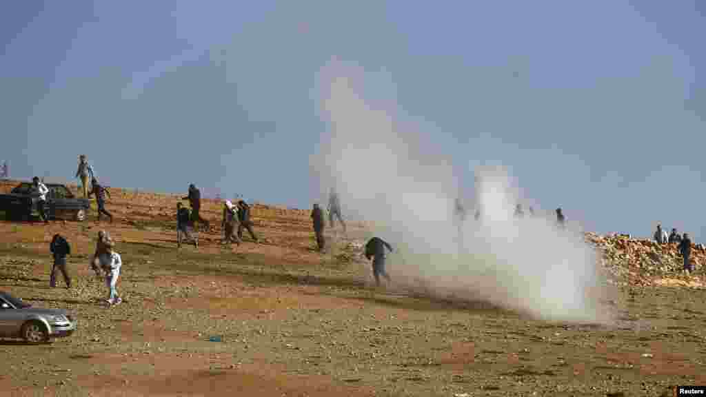 Tear gas canisters fired by Turkish military land amongst observers as they try to clear a hill near the Mursitpinar crossing on the Turkish-Syrian border, Oct. 26, 2014. 