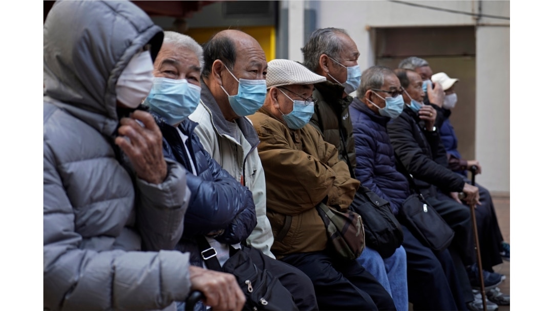 FILE - Elderly men sit at a park wearing face masks in Hong Kong, Jan. 30, 2020.