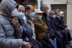 Elderly men sit at a park wearing face masks in Hong Kong, Jan. 30, 2020. Hong Kong cut off rail service to mainland China at midnight on Wednesday to try to stop the spread of the coronavirus to the city.