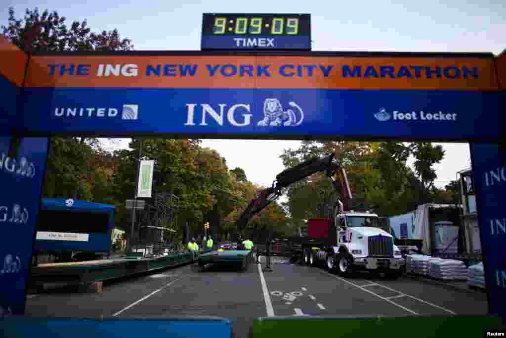 Workers install a platform during the ceremonial painting of the New York City Marathon blue line at Central Park, New York, Oct. 30, 2013.