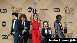 De izquierda a derecha, Finn Wolfhard, Gaten Matarazzo, Millie Bobby Brown (de rojo), Noah Schnapp, y Caleb McLaughlin posan con el premio Screen Actors Guild a la excelencia en la actuación por "Stranger Things". Shrine Auditorium, Los Angeles, 29/1/17.