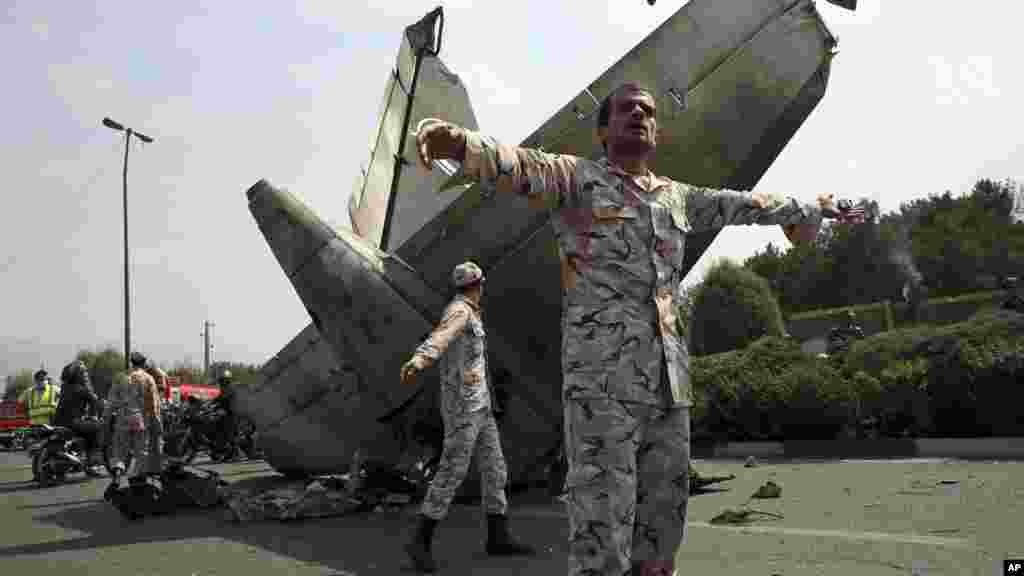 Iranian Revolutionary Guards prevent the media from approaching the wreckage of a passenger plane crash near the capital Tehran, Iran, Sunday, Aug. 10, 2014.